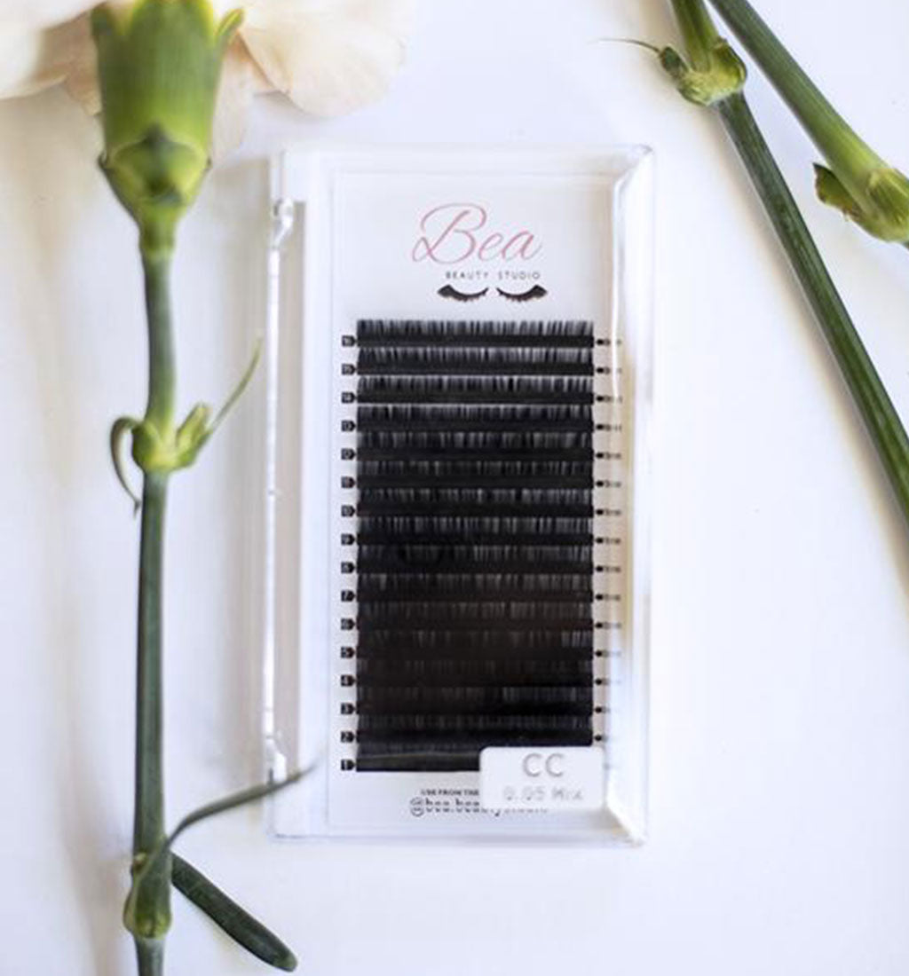 CC Curl Lash Tray .06 lash tray surrounded by flowers on a white background.