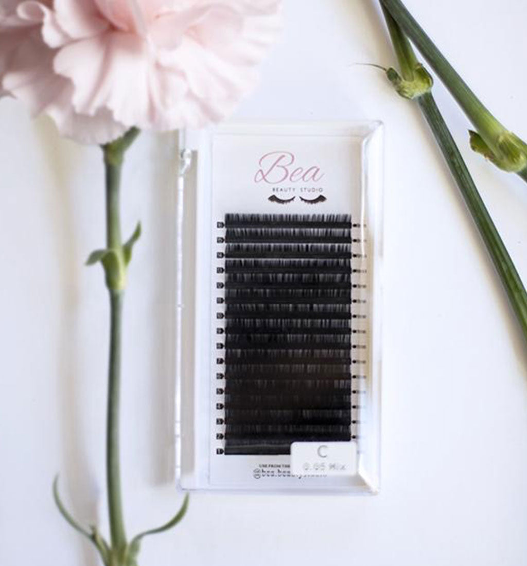 C Curl Lash Tray .06 lash tray surrounded by flowers on a white background.
