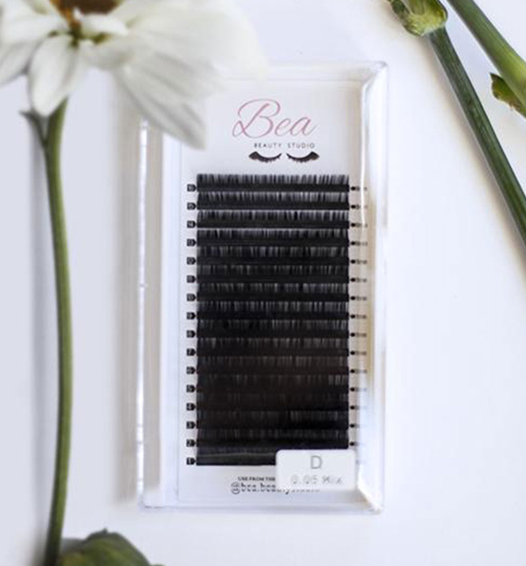 D Curl Lash Tray .03 on a white background  surrounded by flowers.