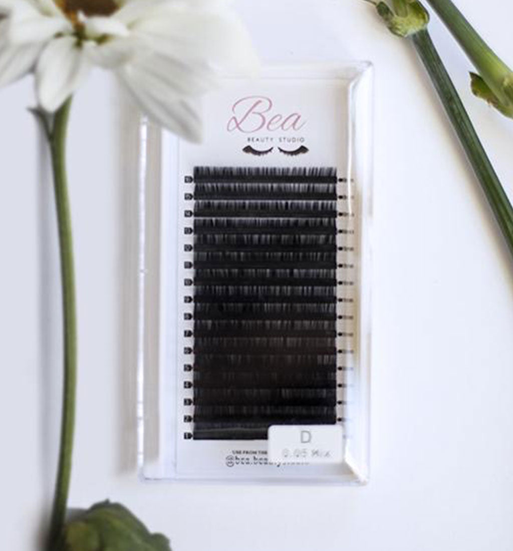 D Curl Lash Tray .06 on a white background  surrounded by flowers.